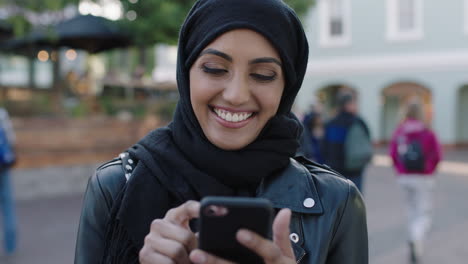 Retrato-De-Una-Joven-Y-Hermosa-Mujer-Musulmana-Usando-Un-Teléfono-Inteligente-Riéndose-Alegremente-De-Los-Mensajes-De-Las-Redes-Sociales