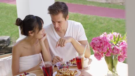 couple talking at breakfast table outside