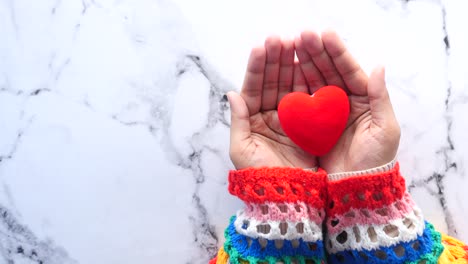 manos sosteniendo un corazón rojo