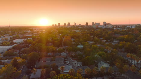 setting sun over beautiful sacramento, california, usa. drone flying over the green cozy city at backdrop of orange sky.