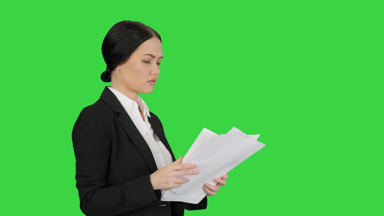 una mujer de negocios linda y seria leyendo documentos en una pantalla verde, llave cromada.