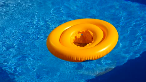 floating ring on blue water of swimpool with waves reflecting in the summer sun