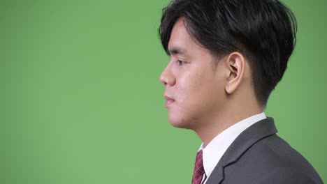 young handsome asian businessman against green background