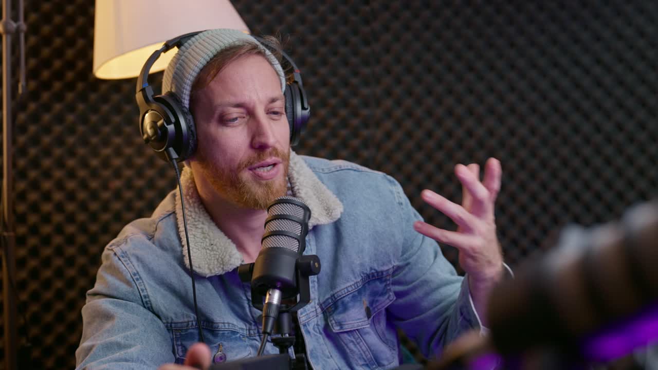 podcaster conversando con un invitado durante un programa en un estudio de podcast profesional. la configuración incluye micrófonos, auriculares, paredes de espuma acústica, iluminación cálida, creando una atmósfera moderna y atractiva