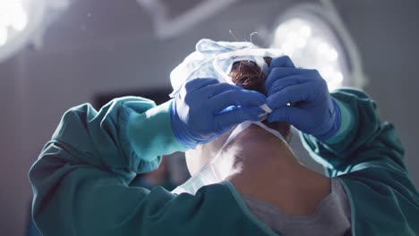 video de vista trasera de una cirujana asiática atando una máscara facial en el quirófano