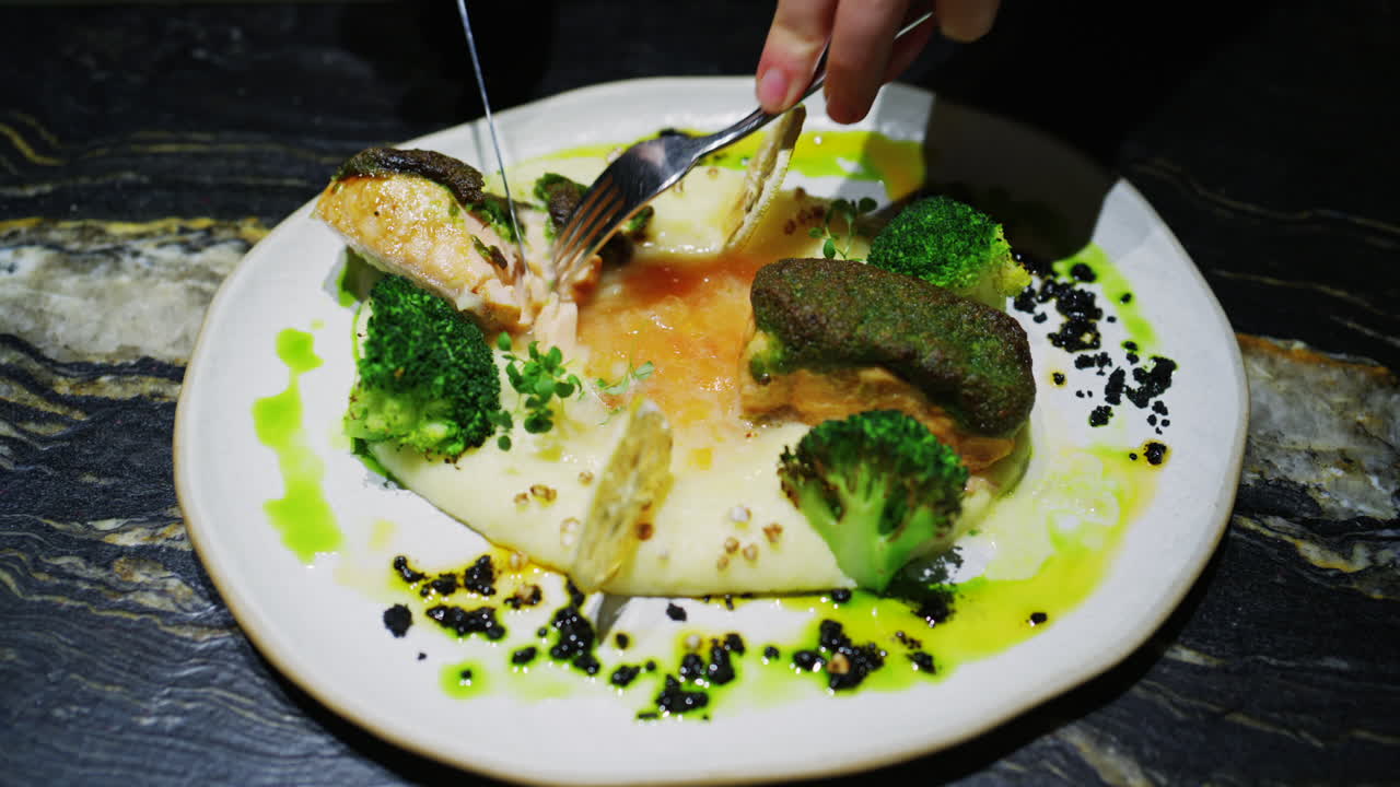 Fine dining plated fish dish with broccoli, creamy puree, herbs, and green sauce