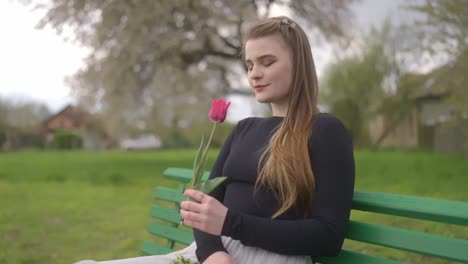 Junges-Mädchen-Mit-Einer-Roten-Tulpe-Wartet-Auf-Ihrer-Liebe-Auf-Einer-Parkbank