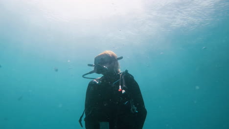 buzo que asciende a la superficie con burbujas y un gran reflejo del sol en el agua