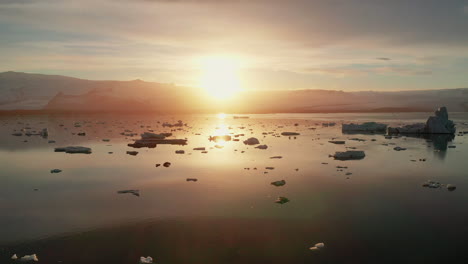 Sunset-over-the-beautiful-calm-Jokusarlon-Glacier-Lagoon-in-South-Iceland---low-aerial