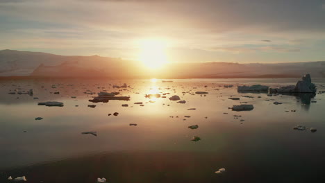 sunset over the beautiful calm jokusarlon glacier lagoon in south iceland - low aerial