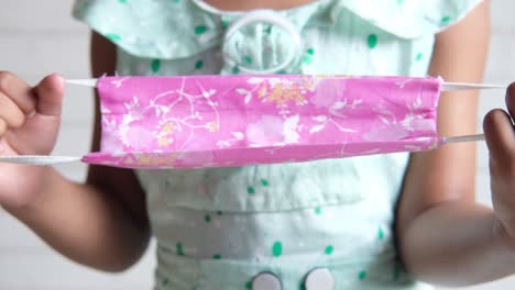 niño con una máscara facial de tela rosada
