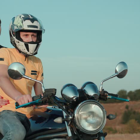 A-guy-and-a-girl-are-sitting-on-a-motorcycle-looking-into-the-distance