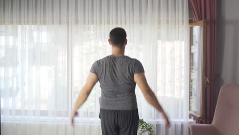 Handsome-active-young-man-doing-cardio-in-living-room.