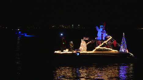 a holiday christmas parade of boats makes its way through a harbor in florida