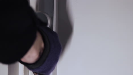 close up shot of a shadowy figure opening a door with a set of keys and wearing gloves