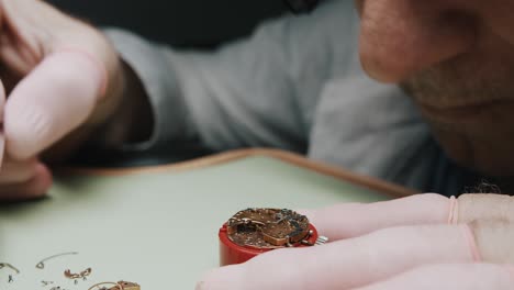 a watchmaker carefully unscrewing the parts of a watch to repair it - close up