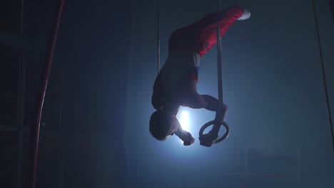 gymnast performing gymnastic cross exercise on gymnastic rings. shot in slow motion.