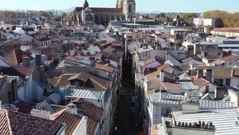 Drone-flying-over-roofs-of-Bayonne-city-center-with-Cathedral-in-background,-France