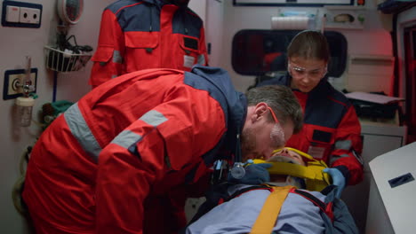 ems paramedics providing first aid procedure to patient in emergency vehicle