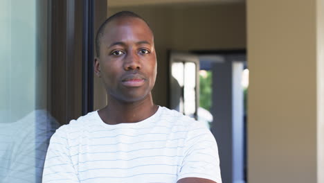 a young african american man stands by a window