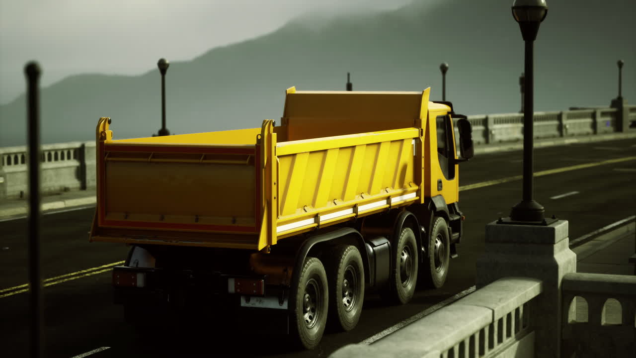 Yellow dump truck navigating an empty coastal road during golden hour