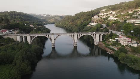 aerial orbiting view cars crossing entre-os-rios bridge over idyllic tamega river