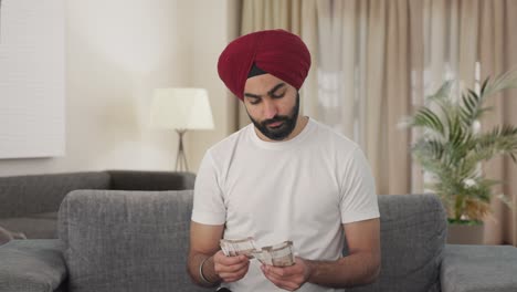 sad sikh indian man counting money