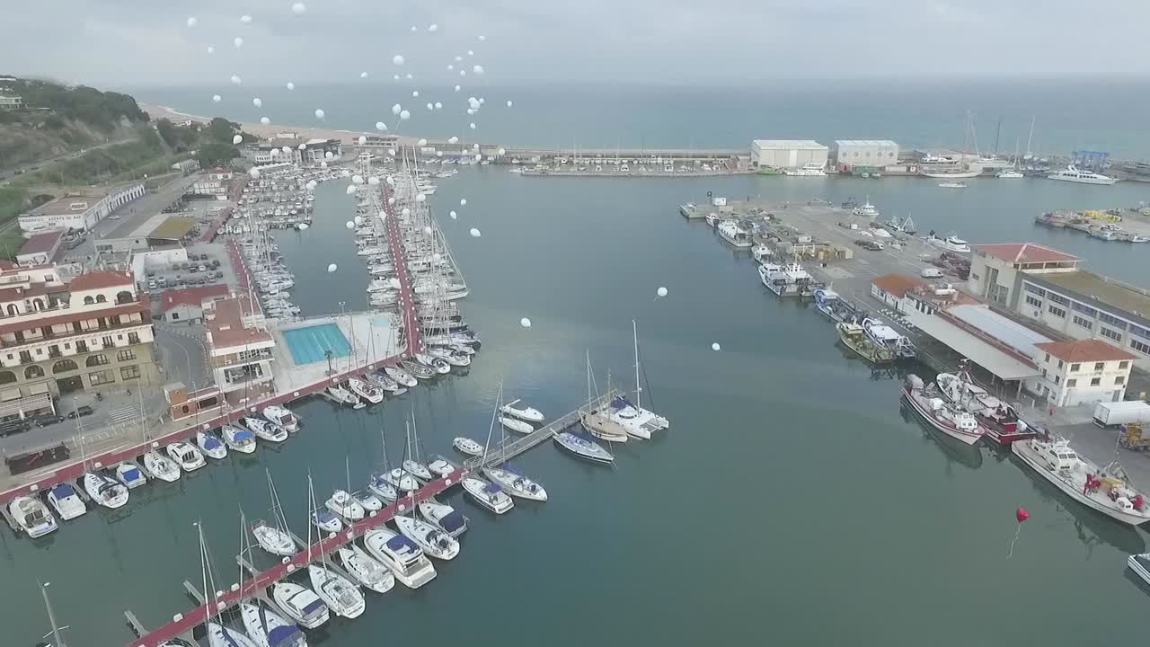 White balloons flying away after wedding ceremony at Arenys de Mar. Aerial