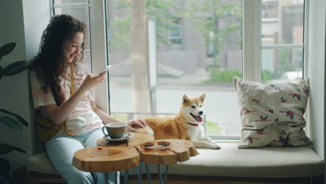woman using phone in a cafe with a dog
