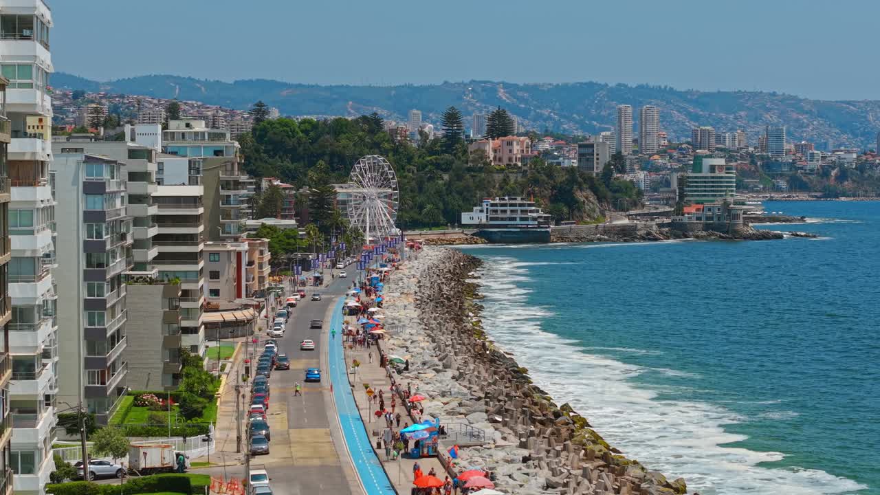 Ripresa aerea panoramica della spiaggia con strada costiera, edifici del resort con le Ande a Av. Perù, Viña del Mar, Cile