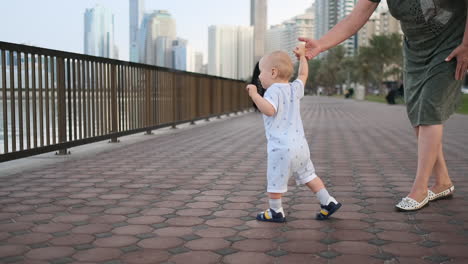 En-Verano,-Una-Joven-Madre-Caminando-Con-Un-Niño-Por-El-Paseo-Marítimo.