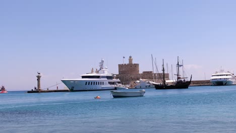 sailing boat going past moored luxury yacht in rhodes harbour