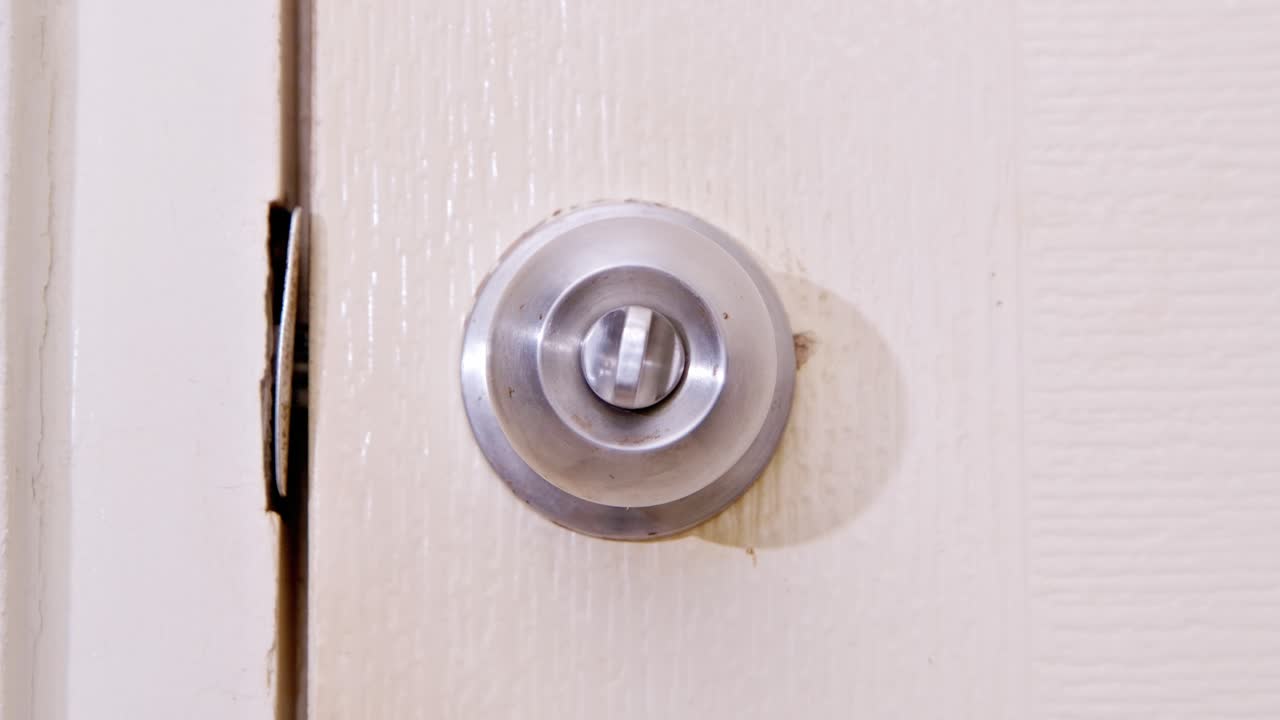 스테인리스 문손잡이를 엄지손가락으로 잠그고 시계방향으로 돌려 문을 여는 남자