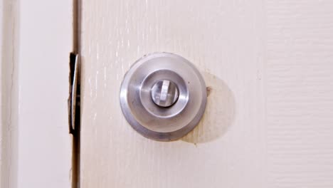 A-man-locking-a-stainless-door-knob-with-his-thumb-and-turning-it-clockwise,-opening-the-door