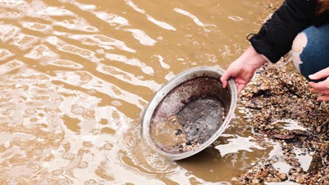 person panning for gold in muddy water