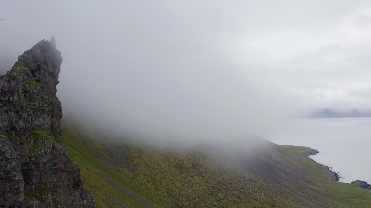 아이슬란드에서 안개 낀 아침 동안 해안 산 풍경 위에 구름