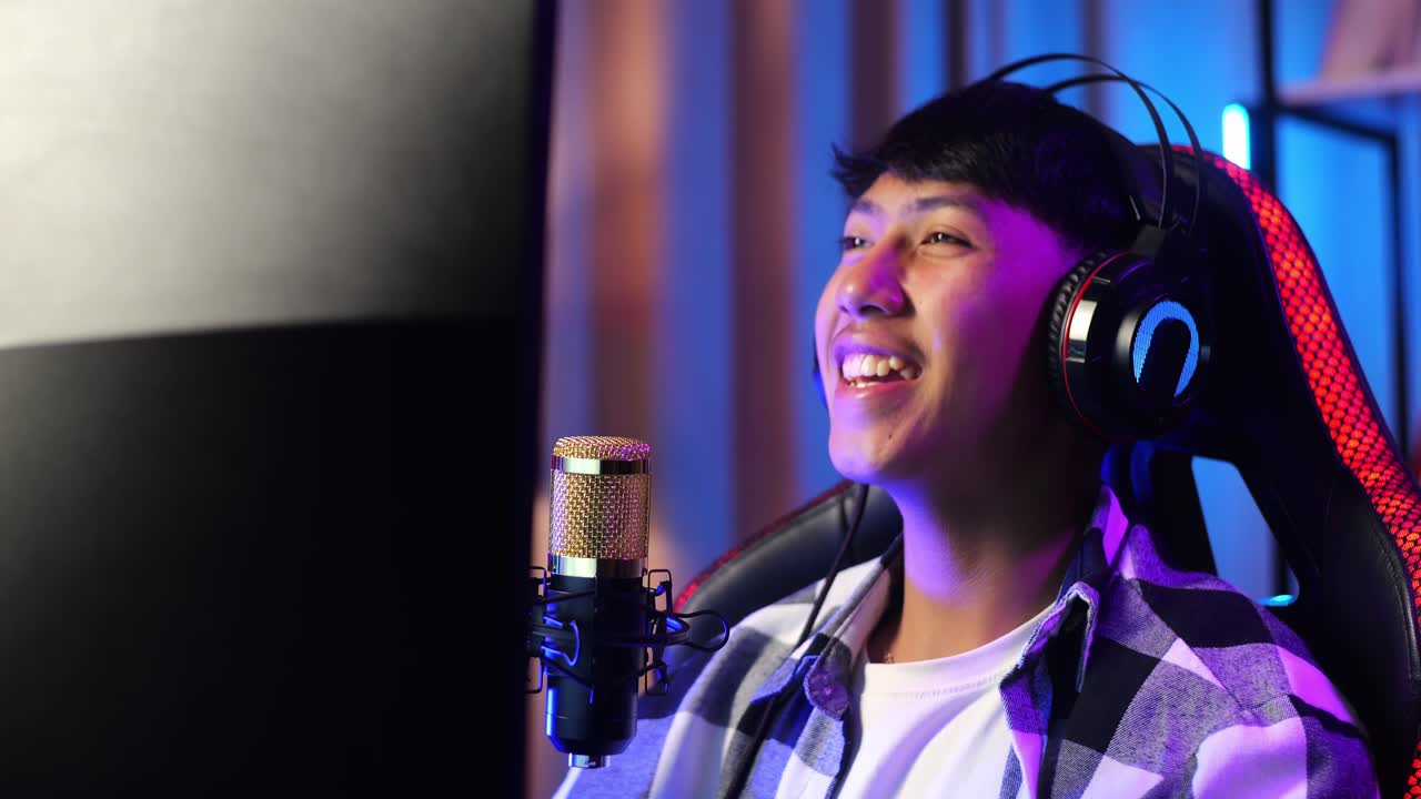 개인 컴퓨터에서 네트워크를 통해 게임을하는 아시아 소년 스트리머, 마이크에서 참가자들과 이야기하는 라이브 스트리밍 비디오 게임, rgb led 스트립 라이트에 의해 조명 된 책상