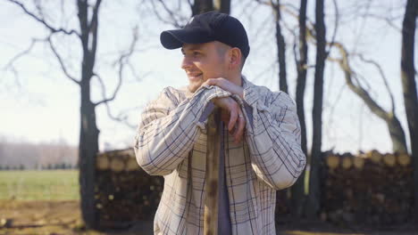 caucasian man leaning on the stick of a rake in the countryside