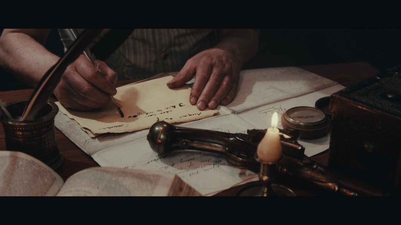 An old captain sits writes a letter inside the sailing ship cabin