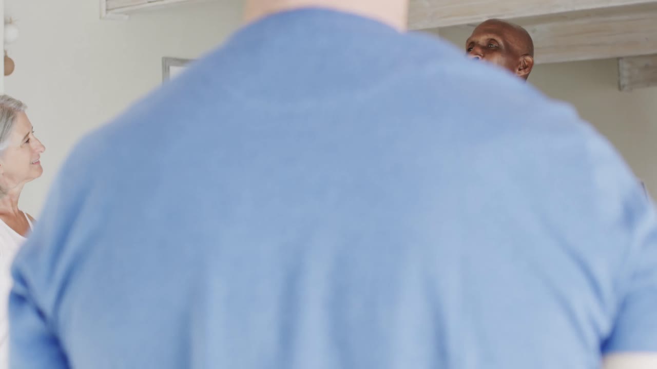 personas mayores felices y diversas de pie y escuchando a un entrenador de pilates masculino, inalterado, en cámara lenta