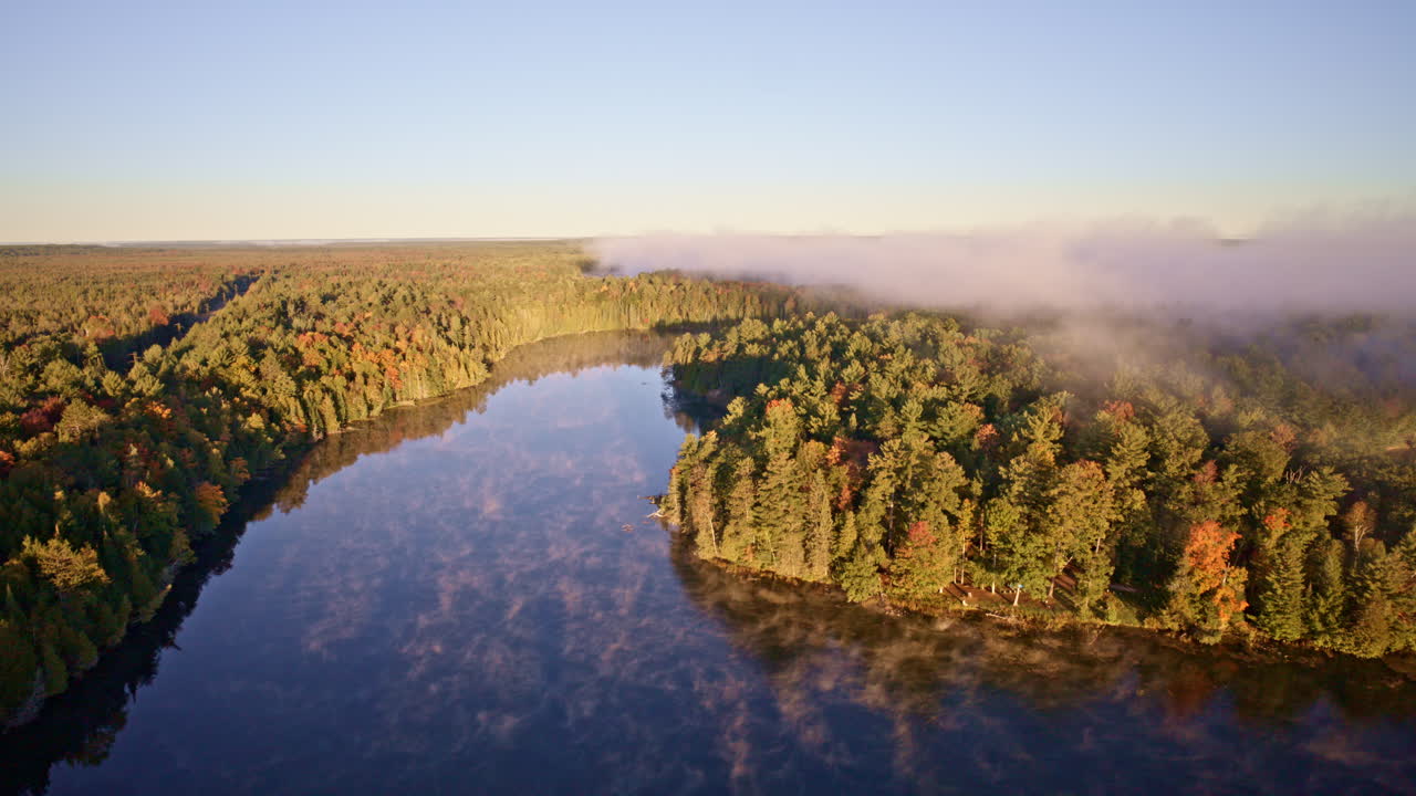 Drone passes above water as morning haze ascends slowly