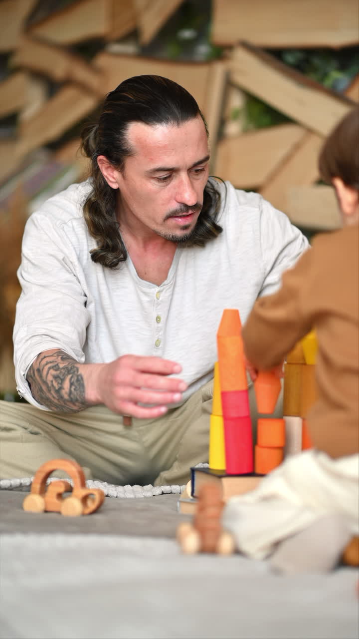 Father playing with his son with colourful, ecological wooden toys on the bed