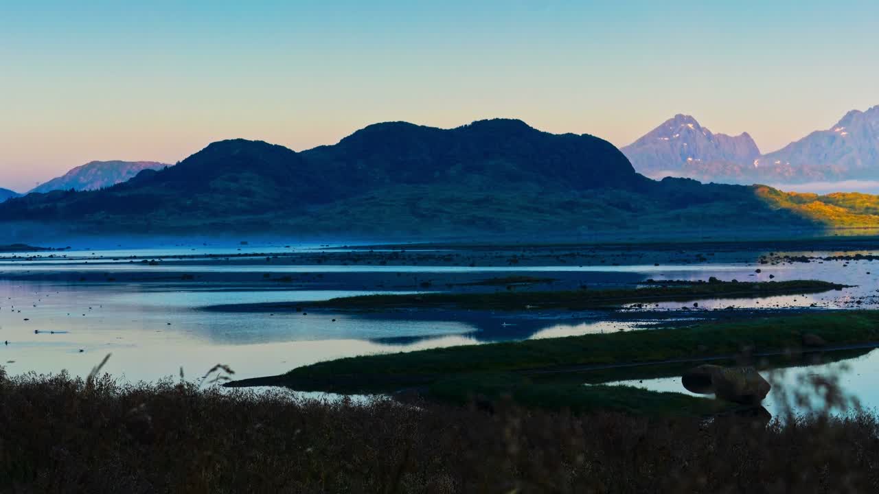 Early summer morning breeze and sea mist on lush island. Sunlight and shadows movements. Time lapse. Lofoten Islands, Northern Norway
