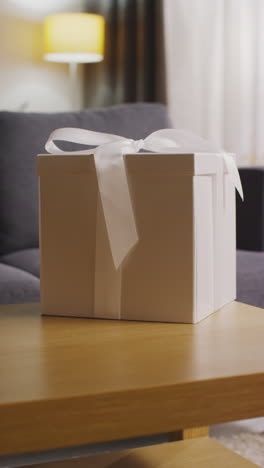 vertical video of present in gift wrapped box decorated with ribbon on table in lounge 3