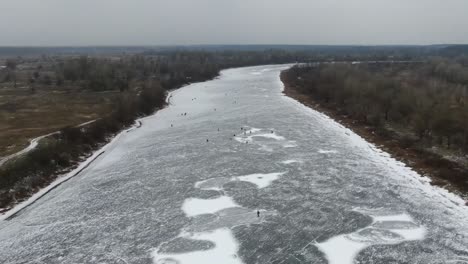 Luftaufnahme-Von-Menschen,-Die-über-Einen-Zugefrorenen-Fluss-Schlittschuh-Laufen