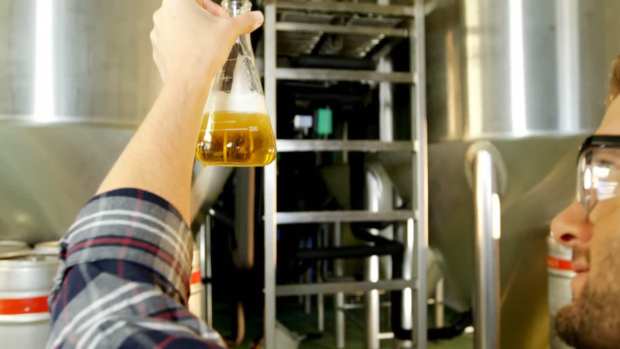 cervecero vertiendo cerveza en un matraz de laboratorio 4k