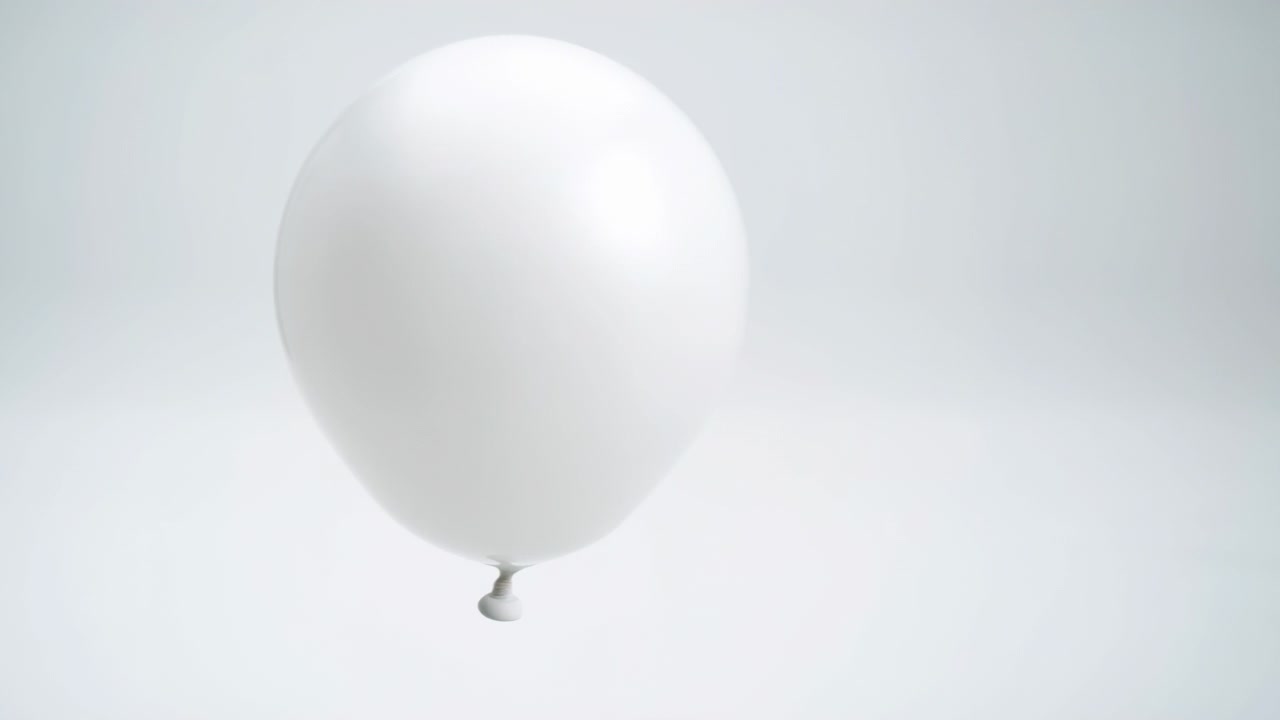 Weißer Ballon schwebt vor einem nahtlosen hellgrauen Studiohintergrund, vollständig aufgeblasen mit glatter, glänzender Oberfläche, abgerundeter Form, weichem, diffusem Glanzlicht, schwachem Schatten und ruhigem, minimalistischem visuellen Stil.