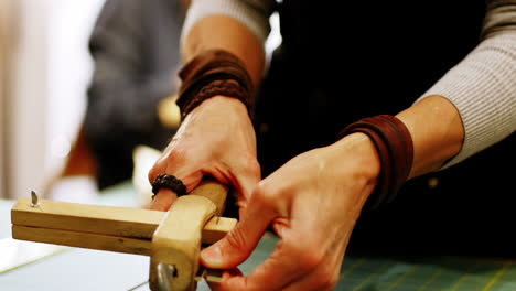 mid-section of craftswoman preparing leather belt