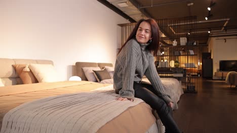 young smiling woman testing new mattress in modern furniture store young smiling woman testing new mattress in modern furniture store high quality footage