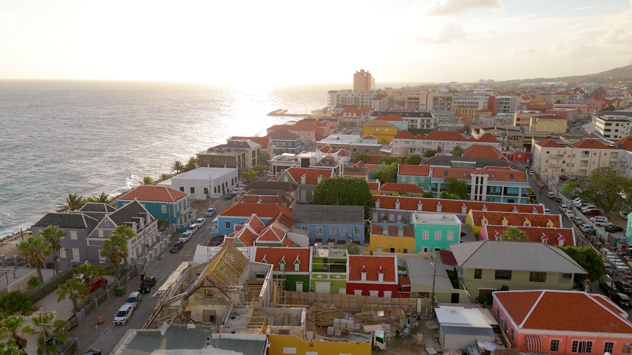 Sunset drone view across Pietermaai featuring colorful heritage buildings along the coast of Willemstad.
